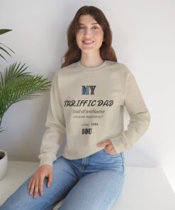 A smiling girl sitting on a couch in her living room wearing a sand color t-shirt showing a My Dad message on the front